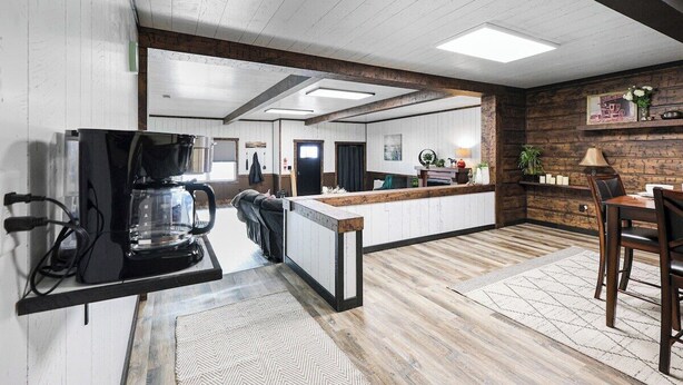 Una cocina con cafetera, encimera y comedor con sillas.