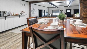 Un comedor con una mesa de madera dispuesta para cuatro personas, rodeada de sillas, con un espejo que refleja la habitación.