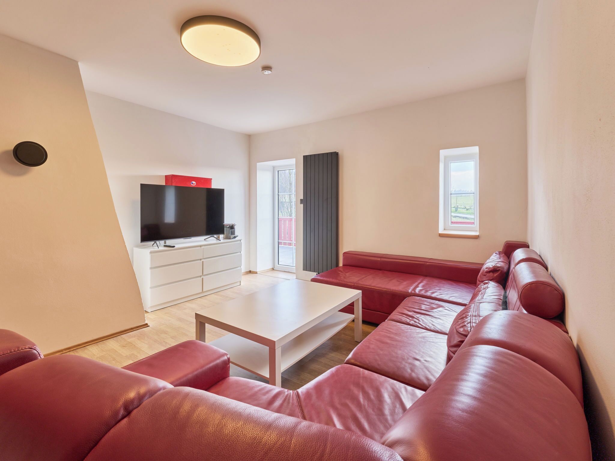 Un salon moderne comprenant un ensemble de canapés, un téléviseur à écran plat, une table basse et une porte-fenêtre coulissante donnant sur un espace extérieur.