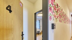 A hallway with a wooden door marked '4', a 'no smoking' sign, and a floral wall mural. - Růžová 4 by Interhome (Ruzova)