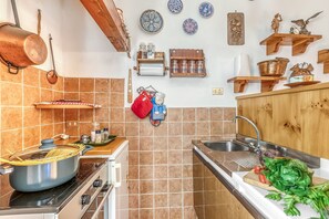 Una cucina con fornello, lavello e diversi utensili.