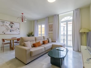 A modern living room with a sofa, coffee table, and dining area. - La Galerie Apartment Living4malaga (Distrito Centro)