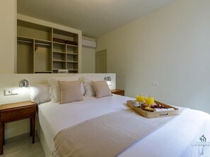A neatly made bed with a tray of breakfast, a bedside table, and a built-in wardrobe.
