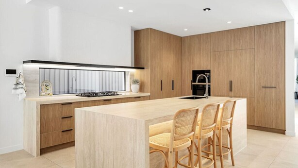 A modern kitchen with a central island, wooden cabinets, and a built-in stove. - Luxe on Sandringham San Souci Sanctuary (Sans Souci)