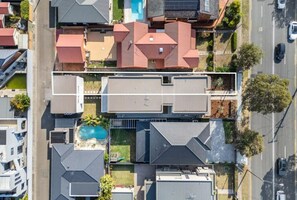 An aerial view of a residential area with multiple houses, a swimming pool, and a road. - Luxe on Sandringham San Souci Sanctuary (Sans Souci)