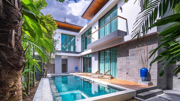 A modern house with a swimming pool, large windows, and tropical plants. - Luxury Teak 4BR Private Pool Villa in Bang Tao (Choeng Thale)