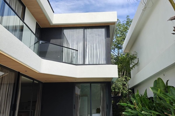 Stylish exterior view highlighting the villa’s upper floor, large windows, and modern design details that enhance natural light.