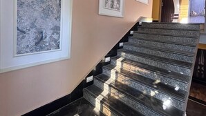 A staircase with black marble steps and white-framed artwork on the walls. - Hotel Mukti Residency (Siliguri)