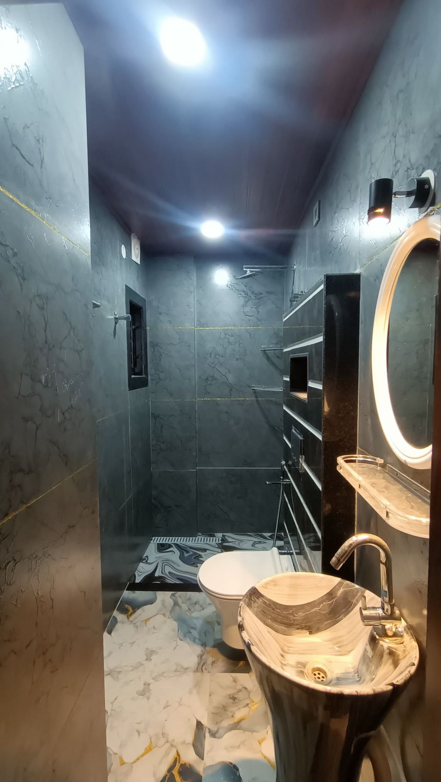 A bathroom with a marble floor, a sink with a wooden basin, a toilet, and a mirror with a light.