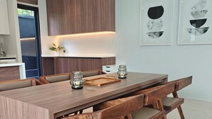Una cocina moderna con una isla central, armarios de madera y una zona de comedor con una mesa grande y bancos.