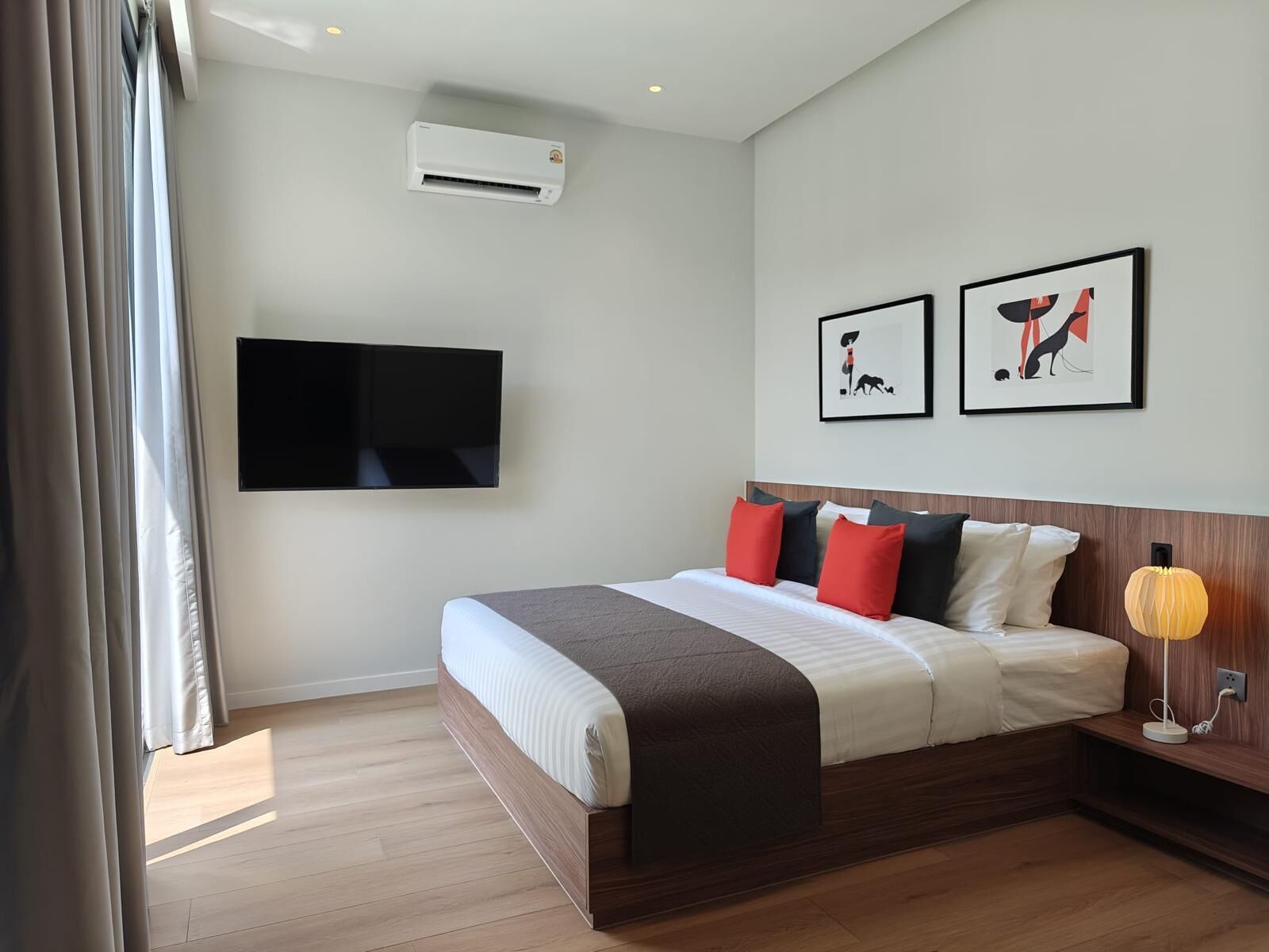 Comfortable bedroom featuring a large bed, wall-mounted TV, air-conditioning, and modern decor.