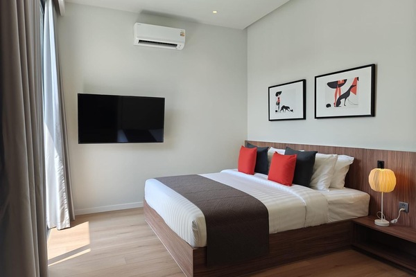 Comfortable bedroom featuring a large bed, wall-mounted TV, air-conditioning, and modern decor.