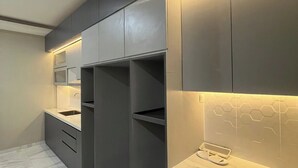 A modern kitchen with dark cabinetry, a marble countertop, and under-cabinet lighting. - El Nipa Hotel Labuan Bajo (Labuan Bajo)