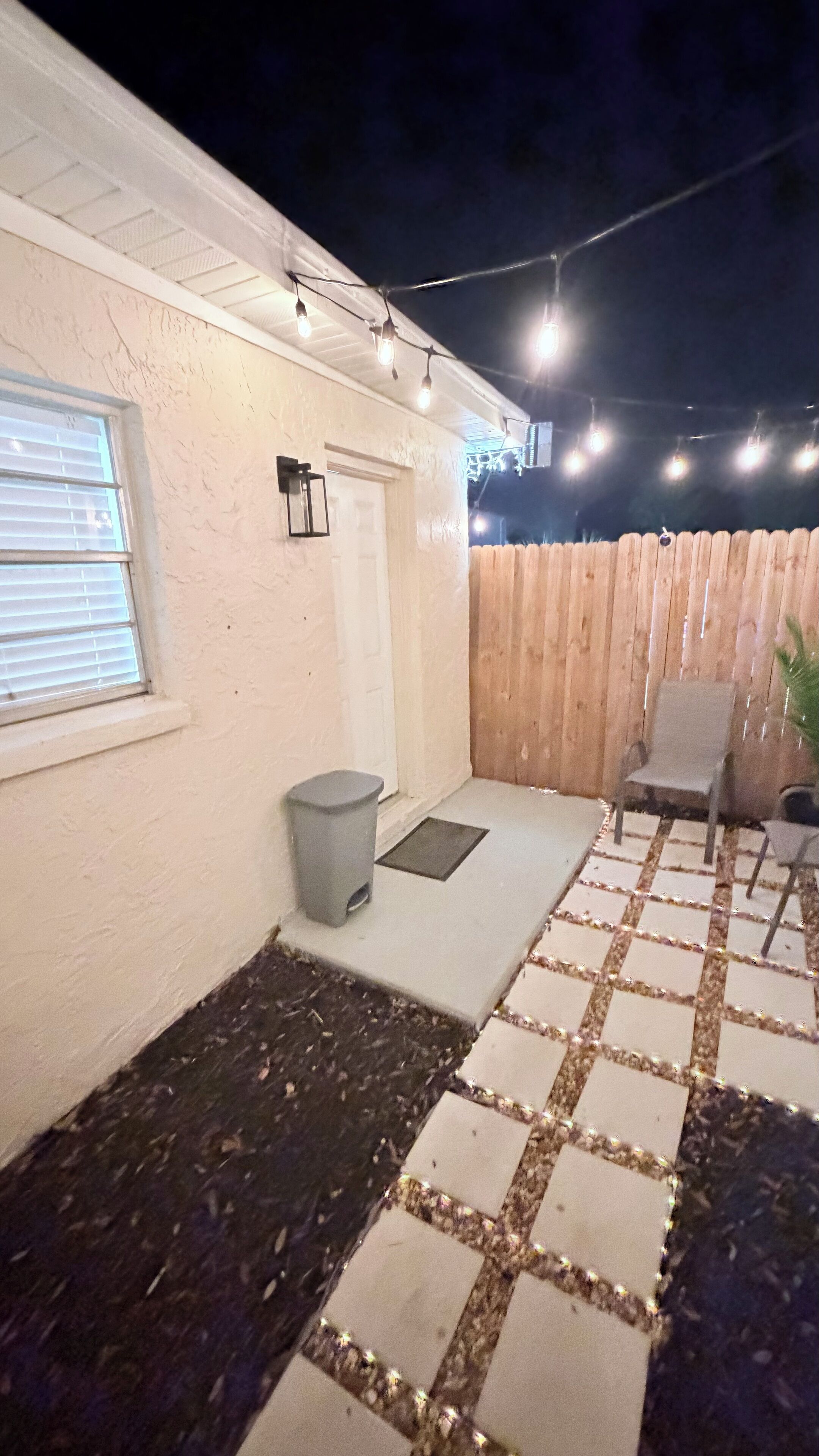 A covered patio area with a wooden fence, a door, and a window.
