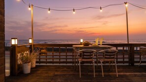 A wooden deck with a table and chairs, overlooking the ocean at sunset. - Haru Stay Donghae (Donghae)