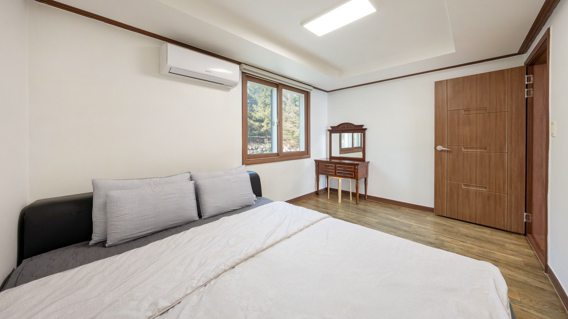 A bedroom with a bed, a dresser, a mirror, and a wardrobe.