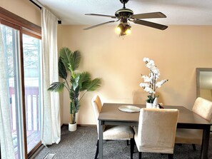 Ein Essbereich mit Deckenventilator, Tisch mit Stühlen, Topfpflanze und Blumenvase.