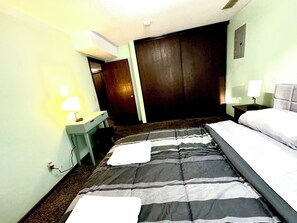 Ein Hotelzimmer mit einem Bett, einem Schreibtisch mit Lampe, einem Kleiderschrank und einem Nachttisch mit Lampe.
