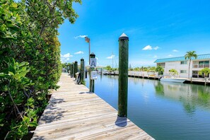 A wooden dock extending into calm water, surrounded by lush greenery and a clear blue sky. - Mar-Key Paradise | 100' Dockage, Atlantic Access & 3 En-Suite Bedrooms (Marathon)