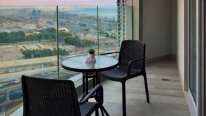Un balcone con un tavolo rotondo e due sedie, vista su un paesaggio urbano con edifici e un'autostrada.