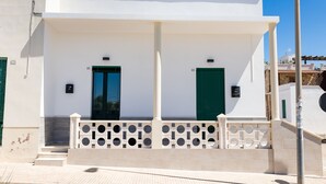 Un edificio bianco con persiane verdi, un portico coperto e un ringhiera decorativa.