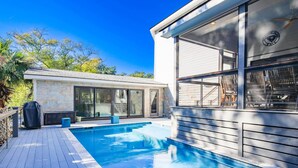 Ett modernt hus med en swimmingpool, stora fönster och en uteplats.