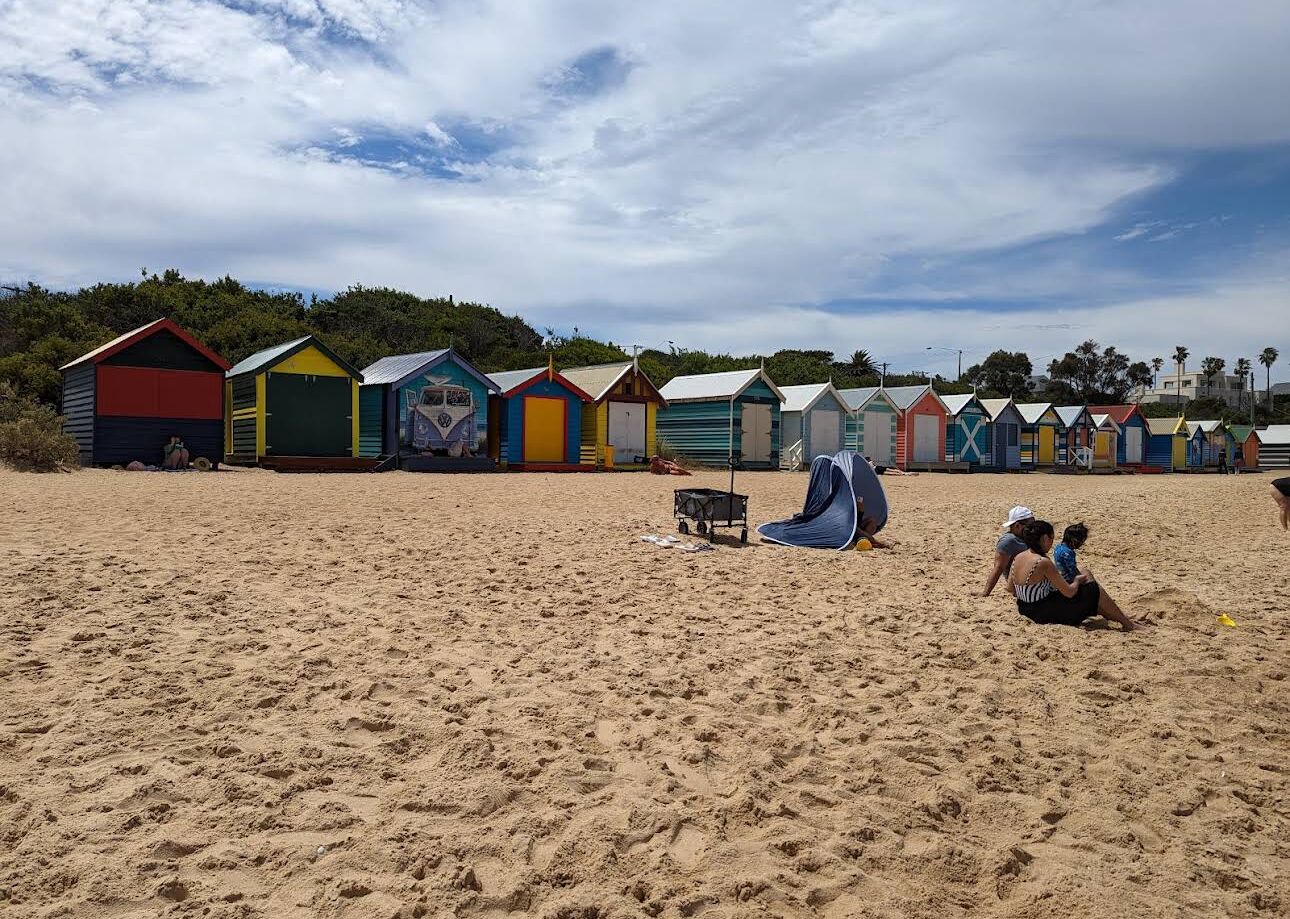 A beach with colorful beach huts and a tent.