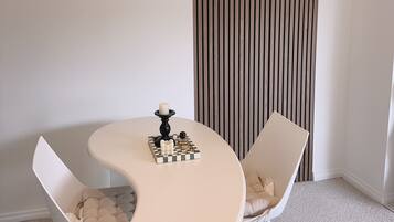 A modern dining area with a round table, two white chairs, a decorative candle centerpiece, and a striped wall.