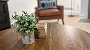 Ein runder Holztisch mit einem kleinen Topfpflanzen und einer Holzkiste.