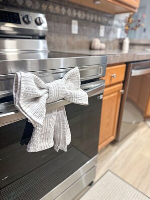 Uma cozinha com eletrodomésticos de aço inoxidável, incluindo um forno com uma toalha branca amarrada em laço.