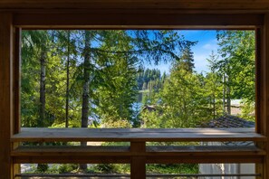 Una finestra con cornice in legno, vista su una foresta e una casa sullo sfondo.