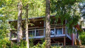 Ein mehrstöckiges Chalet mit Balkon, umgeben von dichtem Wald.