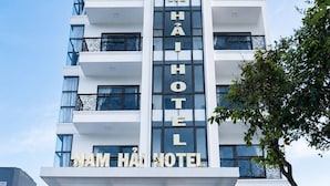 Un h ôtel à plusieurs étages, doté d’une enseigne bien visible indiquant « HÔTEL NAM HÀI » et présentant un design architectural moderne.