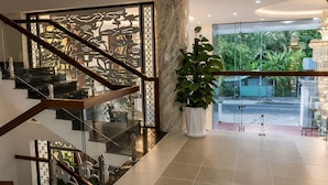 Un intérieur moderne avec un escalier en verre, une plante en pot et une vue sur la verdure à l’extérieur.