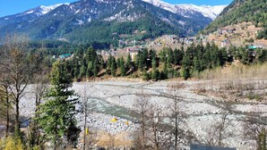 A mountainous landscape with a river, buildings, and snow-capped peaks. - Mountain View -bedroom,  bed & breakfast in welcoming Manali (Manali)