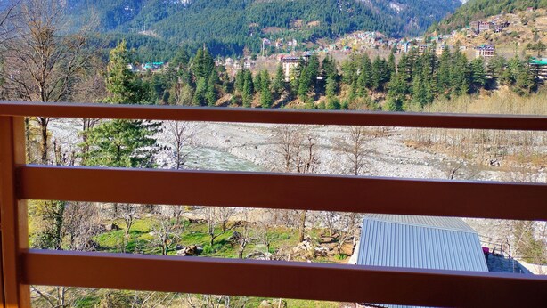A mountainous landscape with a river, buildings, and a clear sky. - Mountain View -bedroom,  bed & breakfast in welcoming Manali (Manali)