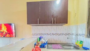 A kitchen with a TV displaying a fire, a sink, cabinets, and various kitchen items. - Sunset Suites Mtwapa (Mtwapa)