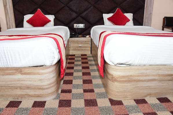 Ein Hotelzimmer mit zwei Betten, jedes mit einem roten Kissen, einem Holz-Kopfteil und einem karierten Boden.