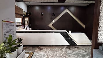 A reception area with a marble floor, a reception desk, and a wall with a geometric design.