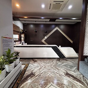 A reception area with a marble floor, a reception desk, and a wall with a geometric design.