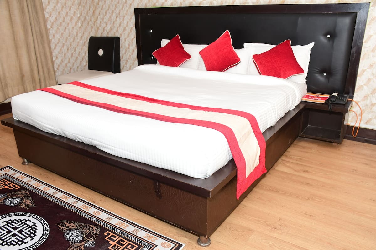 A neatly made bed with a red and white bedspread, a wooden headboard, and a red pillow.