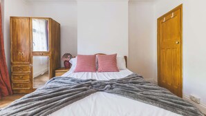 Ein Schlafzimmer mit einem Bett, einem Holzschrank, einem Nachttisch und einer Tür.