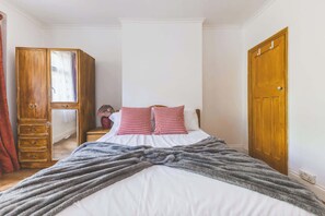 A bedroom with a bed, a wooden wardrobe, a nightstand, and a door. - 1 BDR Flat and Private Garden in Hammersmith (Greater London)