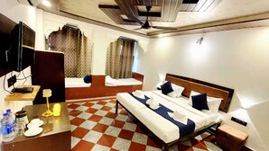 Una habitación de hotel con piso a cuadros, una cama con almohadas, un escritorio con lámpara, un televisor y una pequeña mesa con una botella de agua.
