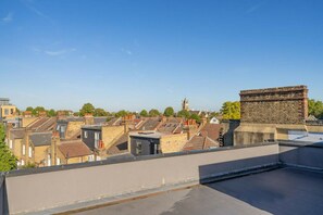 Blick vom Dach auf terrassenförmig angeordnete Häuser, wobei sich rechts eine markante Backsteinstruktur befindet.