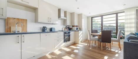 A modern kitchen with white cabinets, a wooden countertop, and a dining area with a table and chairs.