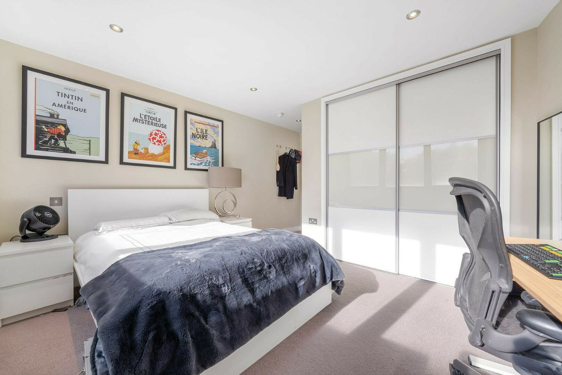 A hotel room with a bed, a desk with a chair, a lamp, and wall art.