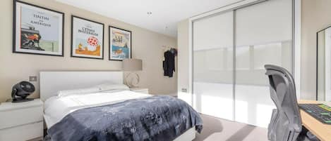 Una habitación de hotel con cama, escritorio con silla, lámpara y decoración en la pared.
