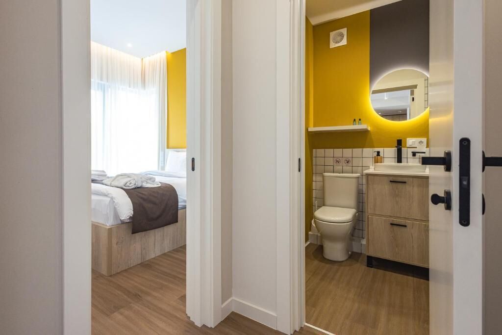A hotel room with a bed, a bathroom with a toilet, and a sink.