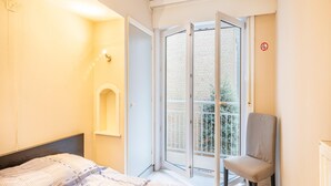 A hotel room with a bed, a chair, a balcony with a view of the outside, and a door with a no-smoking sign. - Cosy flat with frontal sea view (Koksijde)